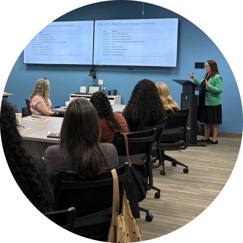 Training for website Mercer employee in green jacket providing training to health center staff