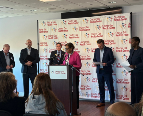 A group of officials speaks at a press conference at Charter Oak Health Center